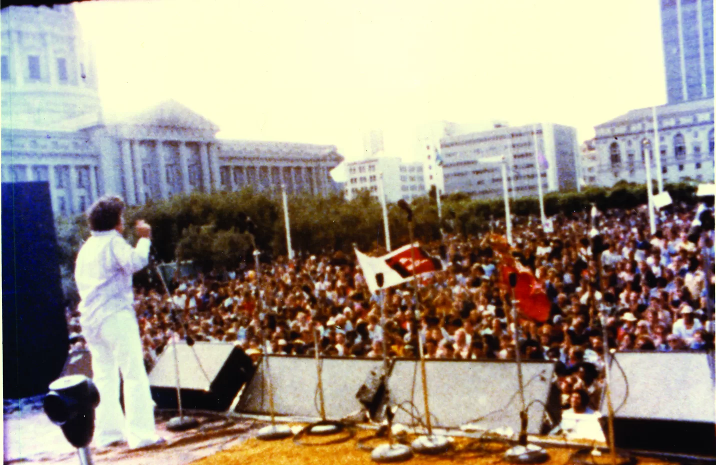 Pessoa a falar num palco em frente a uma multidão na rua