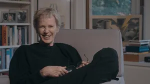 Siri Hustvedt sentada no sofá a rir