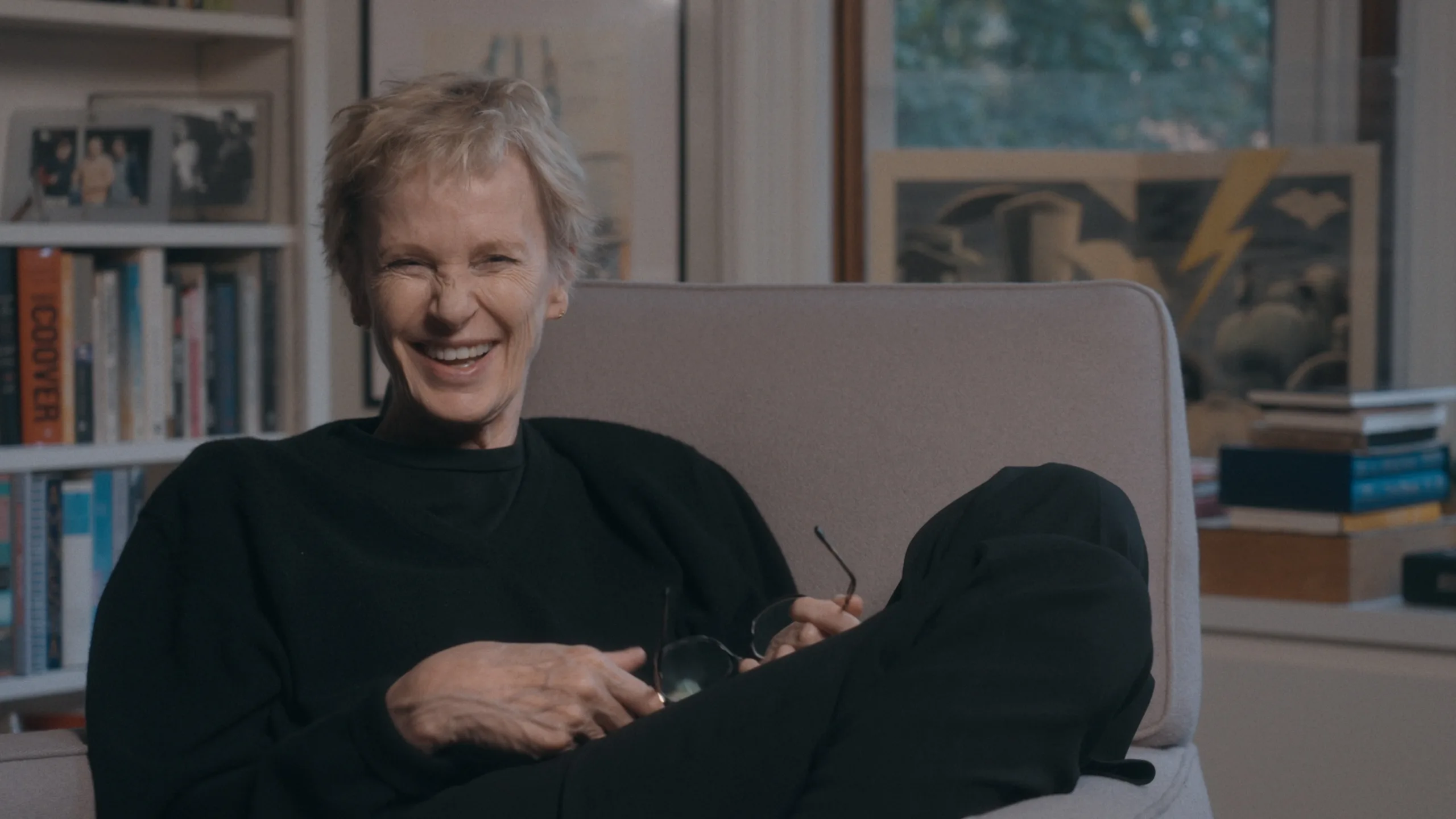 Siri Hustvedt sentada no sofá a rir