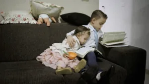 duas crianças no sofá sentadas com livros.