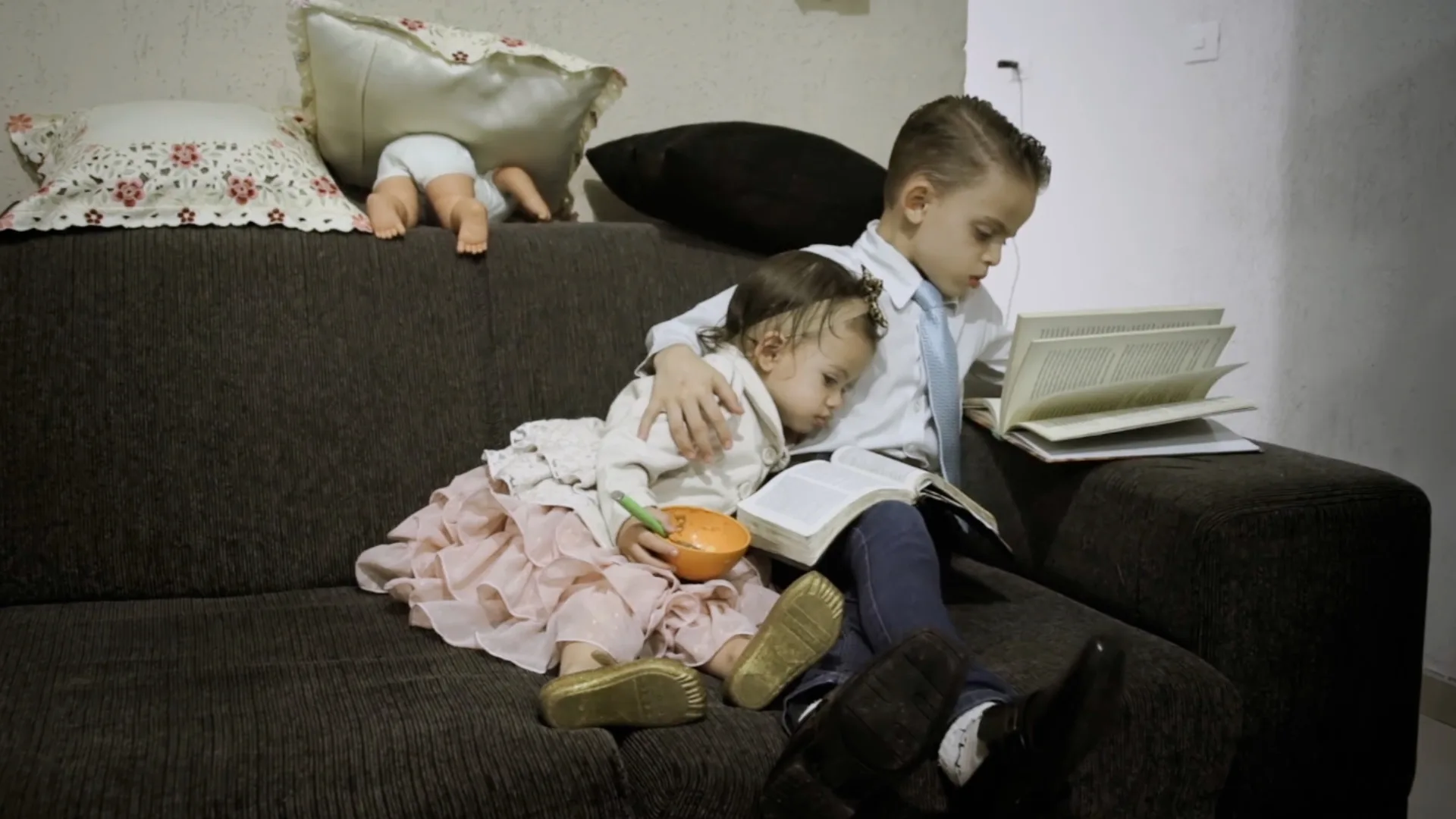 duas crianças no sofá sentadas com livros.
