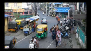 cidade com vários carros, motas e stands de fruta