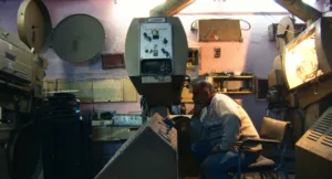 homem a olhar para um projetor de cinema antigo