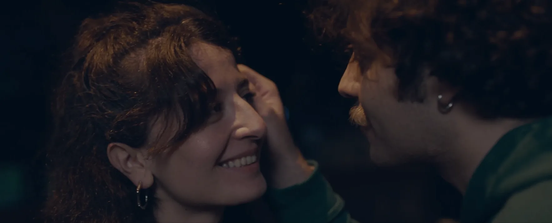 um homem toca na cara de uma mulher e ela sorri
