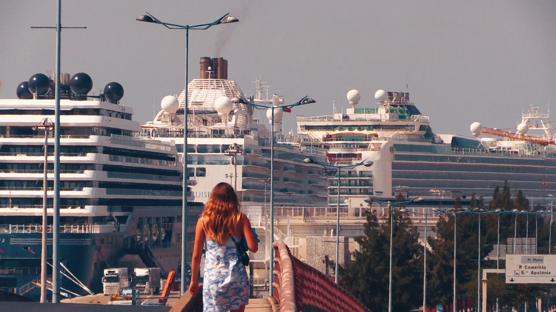 mulher a andar e vários navios ao fundo